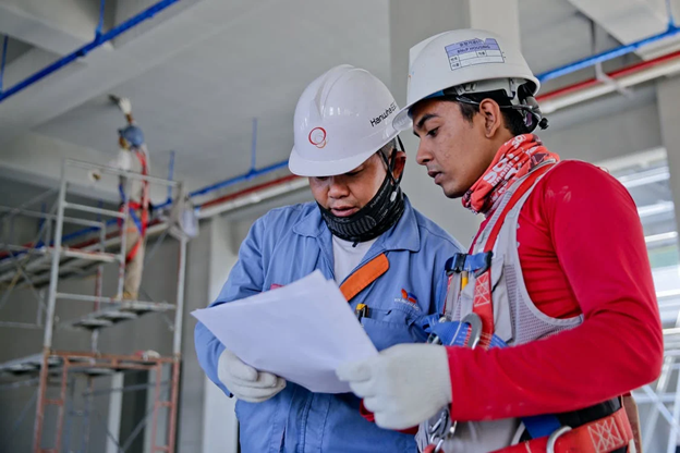 Two construction contractors looking at paperwork, discussing methods